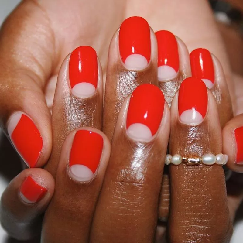 Rote Nägel mit Negativraum-Halbmond-Design an den Nagelhäuten