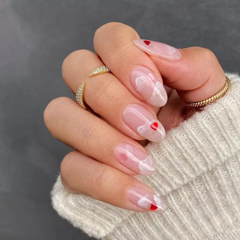 Transparente Nägel mit schillernden Wolkendetails und roten Herz-Nagelaufklebern
