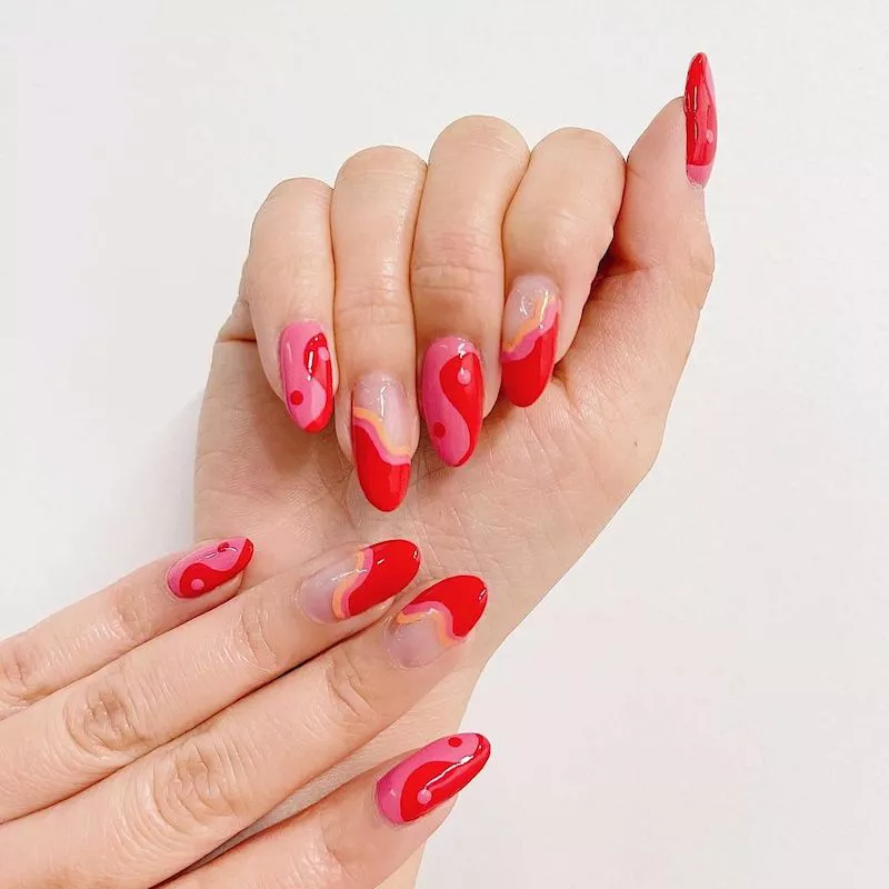 Pfirsichfarbene, rosa und rote Nägel mit Yin/Yang- und Wellendesigns