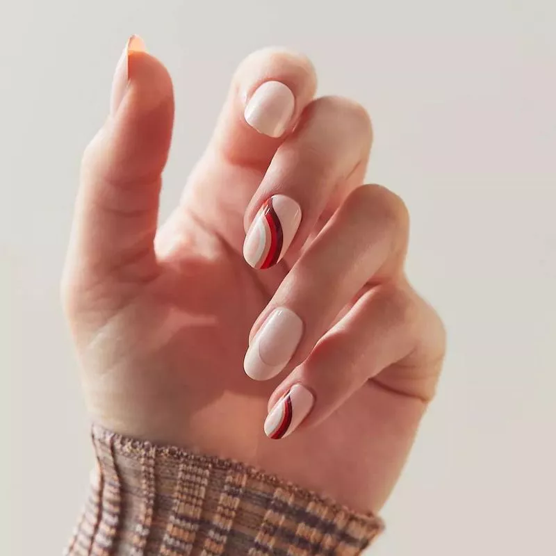 Maniküre mit neutraler Basis und rot-braunem Wellendesign