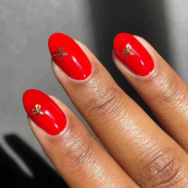 Rote Maniküre mit goldenen Schleifendesigns