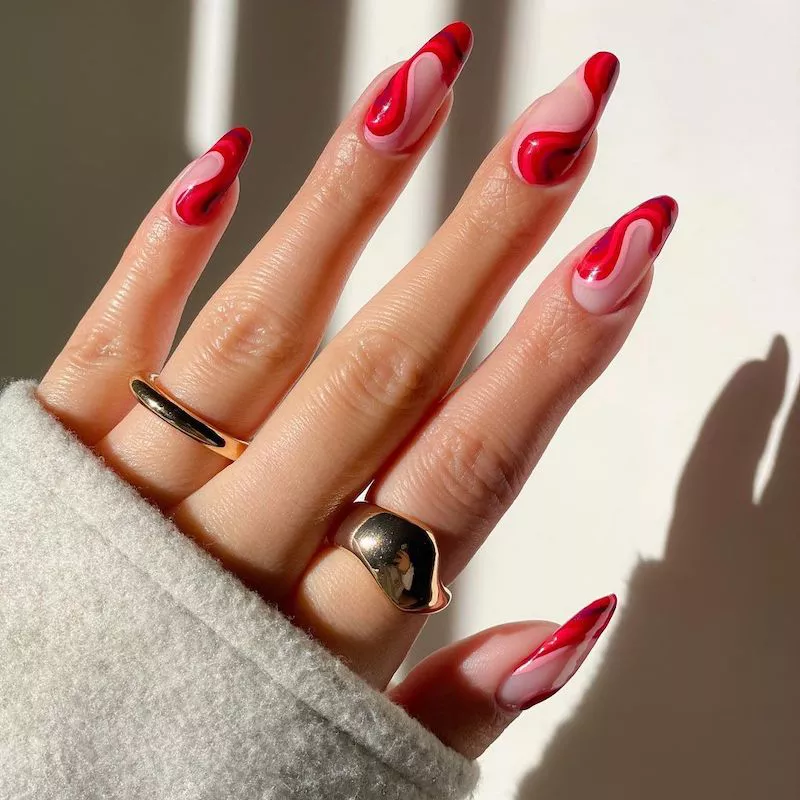 Maniküre mit rotem Wellendesign und goldenen Ringen